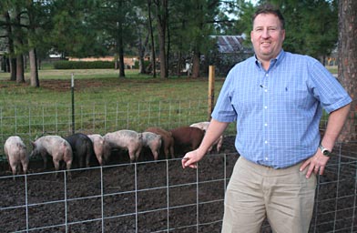 Craig Baker stands in front of the pig pen he's built. The land owned by the Katy Islamic Association is directly behind the pen.
(Michael May)