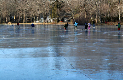 
                    Neighborhood kids skating on Nash's Pond the only weekend skating conditions were good this winter. The long pressure crack in the foreground is a sign that the ice is deeply frozen. And the white house in the background is where Hillary used to trespass to get on the pond.
                                            (Stacy Fowle)
                                        