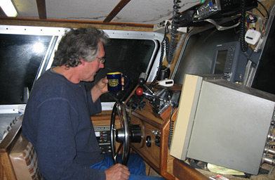 
                    Ernie drinks a lot of coffee, because most of his fishing is done at night.  The monitor to his left is a "chromoscope," that tells him what's swimming under his boat.
                                            (Krissy Clark)
                                        