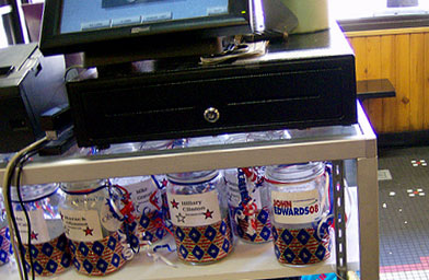 
                    The jars for the Coffee Bean Caucus used to be on the walls, but since there are so many candidates from both parties, they are now kept under the register because they kept getting bumped and shattering on the ground.
                                            (John Moe)
                                        