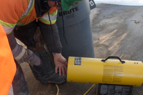 
                    A worker warms his hands with a portable heater.
                                            (Marc Sanchez)
                                        