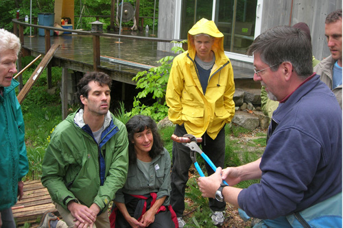 
                    Peter Adams teaches some of the volunteers basic plumbing skills so they can help install the copper pipe system that conducts heat between rooftop solar tubes and a basement water heater.
                                            (Shannon Mullen)
                                        