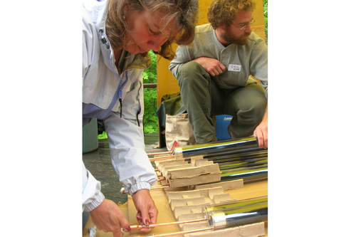
                    Volunteer Carolyn Hemingway applies heat-transfer paste to the solar tubes to prep them for installation.
                                            (Shannon Mullen)
                                        