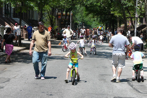 
                    Parents looking on as their kids practice balancing on their bikes.
                                            (Kate Hinds)
                                        