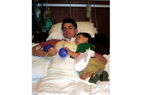 Justin Logan in rehab with his son Michael. The mitt on his left hand was to prevent him from pulling out his feeding tube or hurting staff when he lashed out.
(Courtesy Judi Logan)