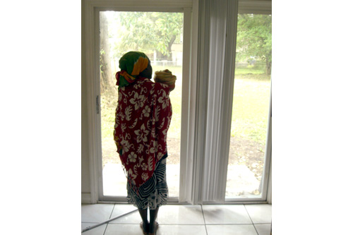
                    Marie Nadine Pierre and her 18-month-old daughter look out into the spacious yard of their new home.  Take Back the Land helped them move into this foreclose vacant house, illegally.
                                            (Andrew Stelzer)
                                        