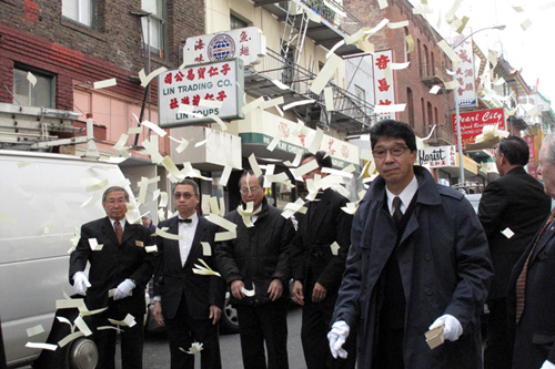 
                    Mourners toss paper money into the air. It's an old tradition called "paying the road," intended to distract unfriendly ghosts, and to provide material support for the deceased ancestor in the spirit world.
                                            (Julie Caine)
                                        