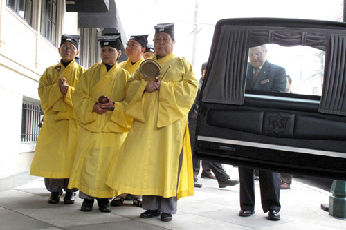 
                    Monks wait outside the Green Street Mortuary before the coffin is brought out to the hearse.
                                            (Julie Caine)
                                        